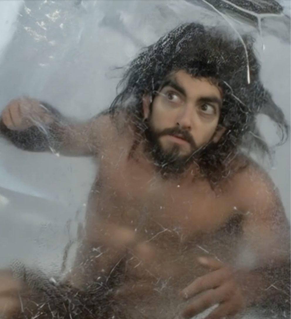A caveman looking out from inside a block of ice